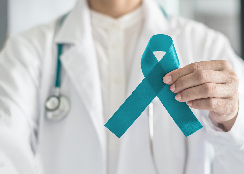 Doctor holding light teal ribbon for cervical cancer awareness month
