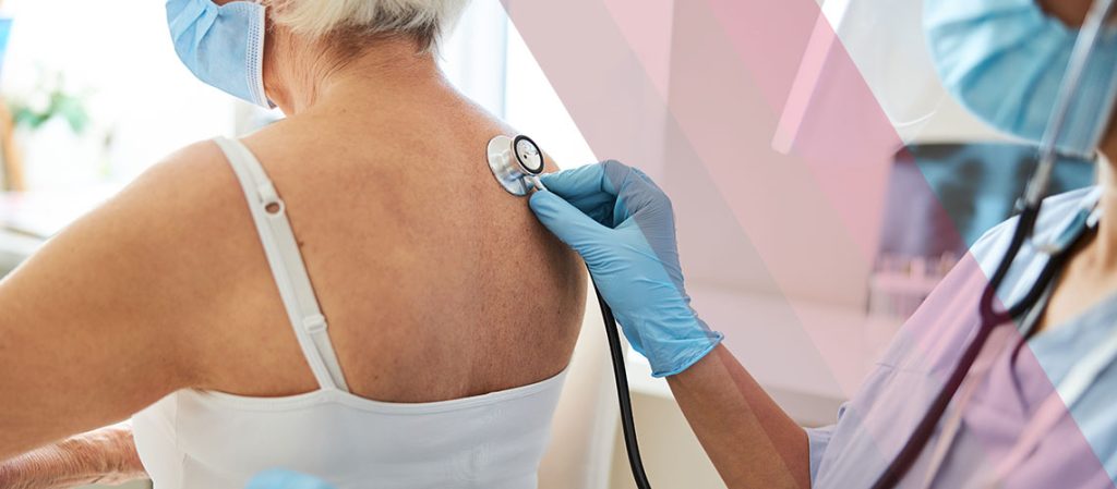 Clinician using a stethoscope to listen to an older woman's lungs during a physical exam