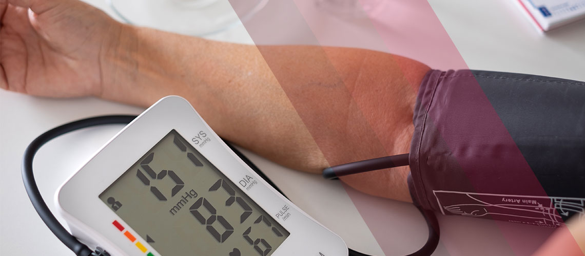 A person checking their blood pressure with an automatic upper-arm cuff monitor